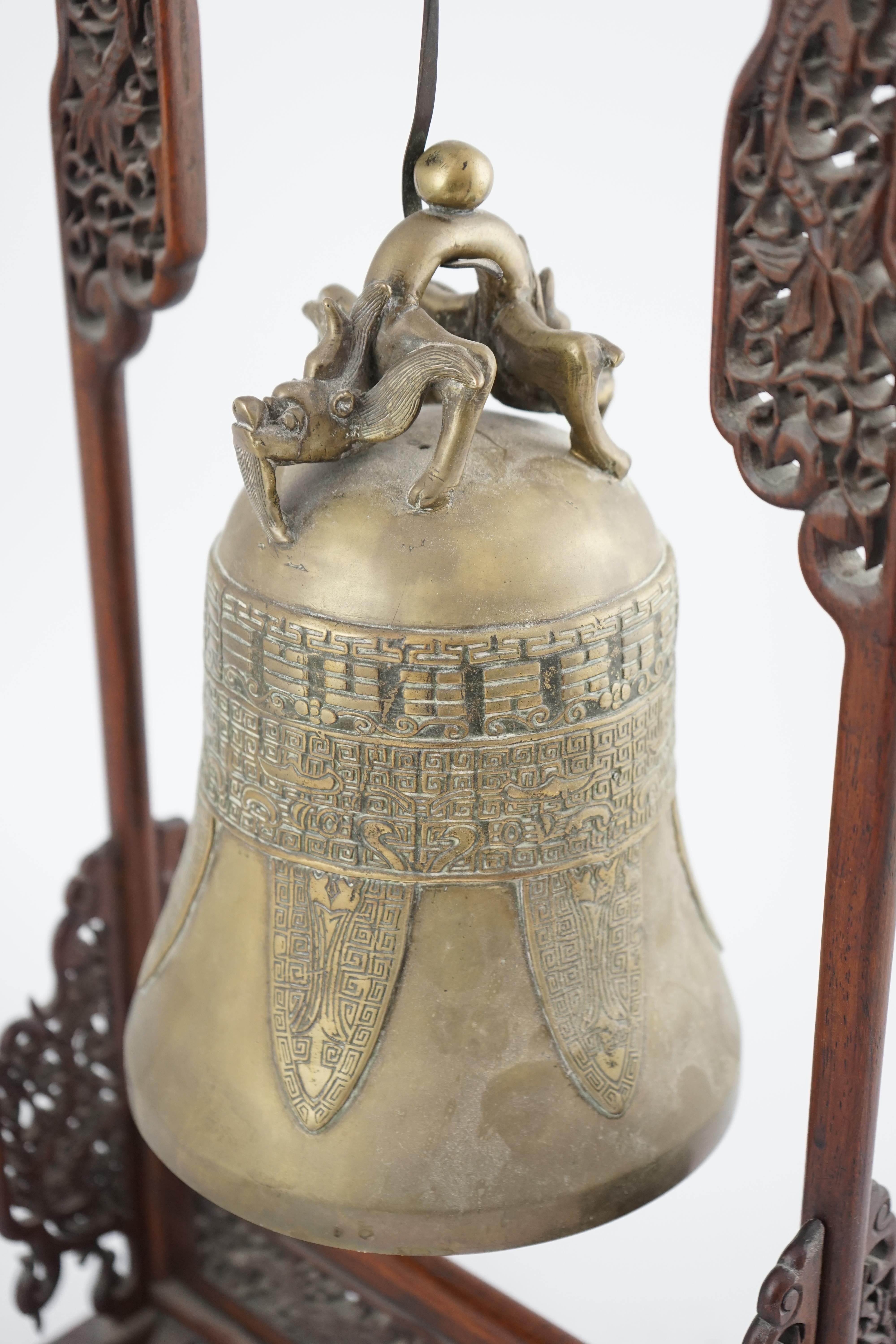 A Chinese archaistic bronze temple bell, and reticulated hardwood stand, Qing dynasty